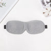 A gray 3D sleep mask is shown lying on a white surface.