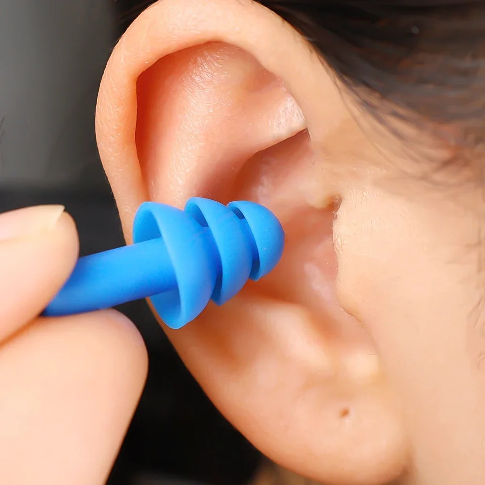 Une main insère un bouchon d'oreille en silicone bleu dans l'oreille d'une personne.