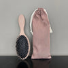 A set of matte boar bristle hair extension brushes, including a paddle brush and a cylindrical brush, displayed against a gra