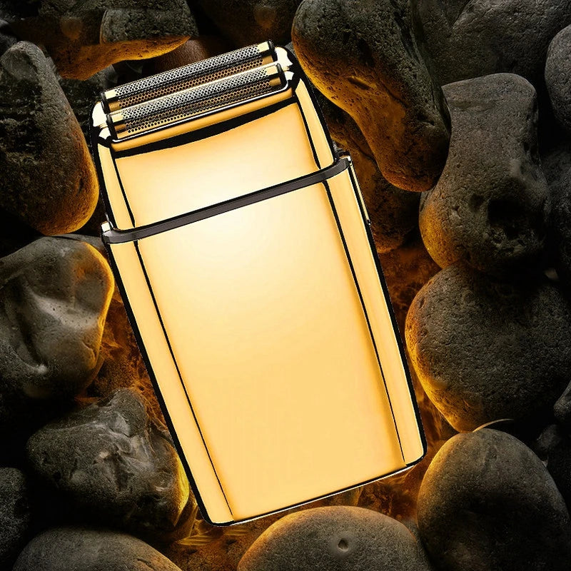 A professional rechargeable electric shaver with a gold-toned body is shown resting on dark, smooth stones.