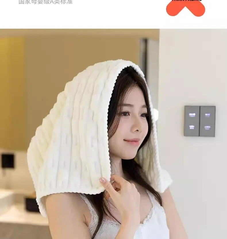 Une femme porte une serviette de bain en velours de bambou blanc drapée sur sa tête dans un intérieur lumineux.