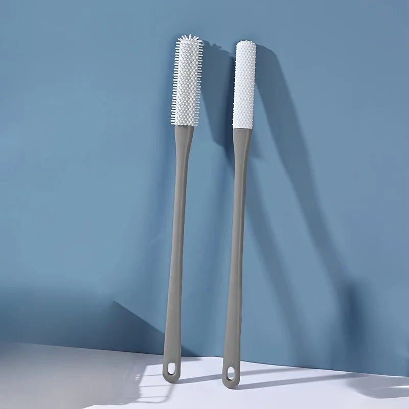 Two white bristled foot scrubbers are displayed against a blue wall with shadows.