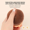 Une main tient un grand pinceau de maquillage brun et duveteux pour l'application sur le corps.