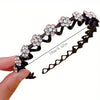 Black rhinestone wave headband featuring floral embellishments, shown being held by a hand.