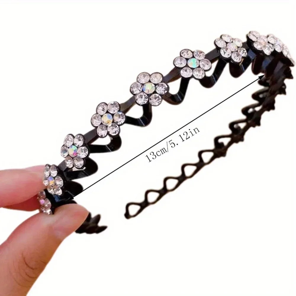 Black rhinestone wave headband featuring floral embellishments, shown being held by a hand.