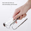 A hand is cleaning a stainless steel U-shaped tongue scraper with water.