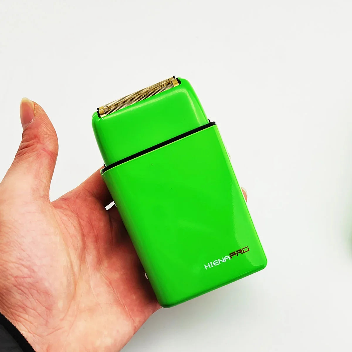 A hand holds a bright green HIENA Pro hair trimmer device against a white background.