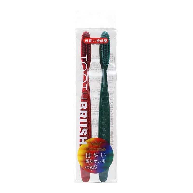 Un set de deux brosses à dents en poils verts et rouges emballées dans un étui en plastique transparent.
