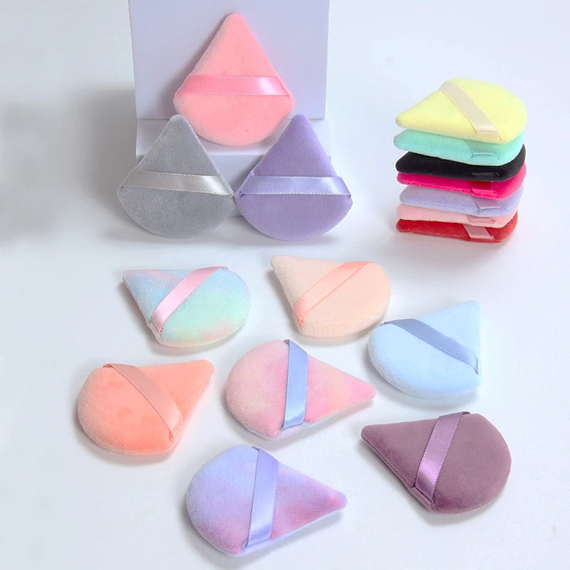 Un set de six éponges de maquillage triangulaires dans diverses couleurs pastel : rose, violet, jaune, vert, bleu et rouge.