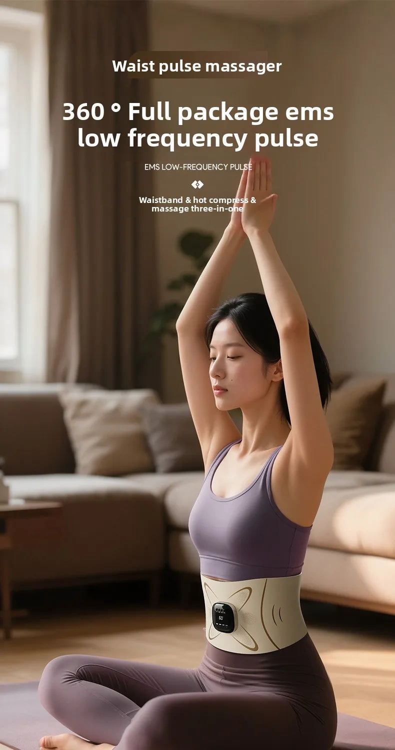 A woman is using an EMS waist pulse massager device on her abdomen while sitting on a yoga mat.