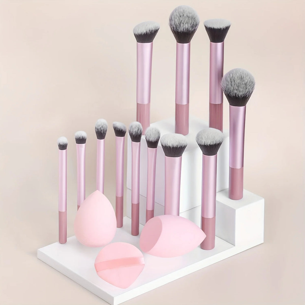 Un juego de doce brochas de maquillaje profesionales en rosa y gris expuestas en un soporte blanco.