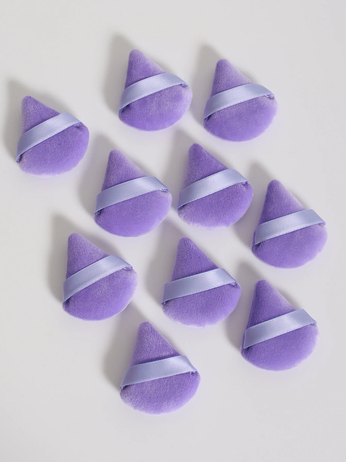 Un ensemble de touffes de poudre triangulaires violettes avec des rubans de satin violet clair.