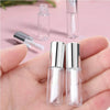 Two clear glass lip gloss tubes with silver caps are shown in a hand, alongside an empty glass bottle.