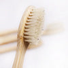 A close-up view of an eco-friendly bamboo toothbrush with natural bristles against a white background.