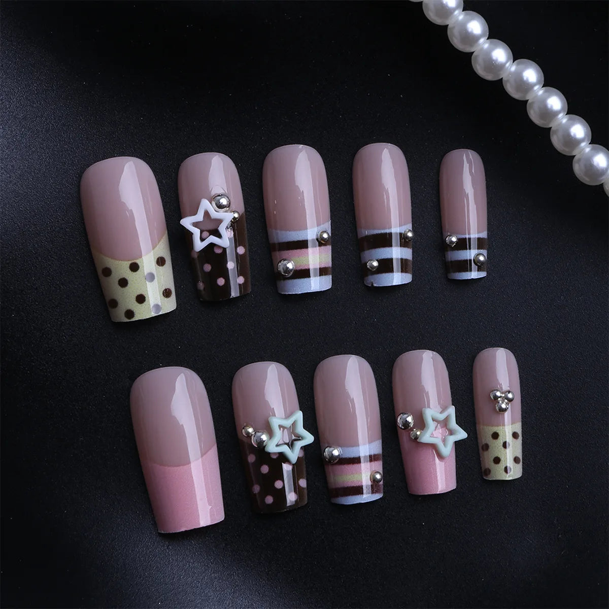 Press-on nails featuring a pink and brown French wave design with star accents on a black background.