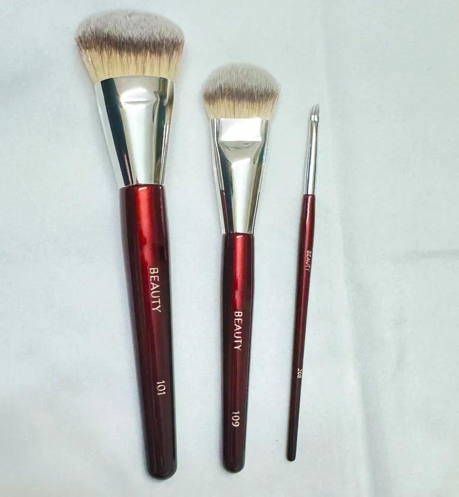 Un jeu de trois pinceaux de maquillage pour fond de teint anglés avec des ferrules argentées et des manches marron.