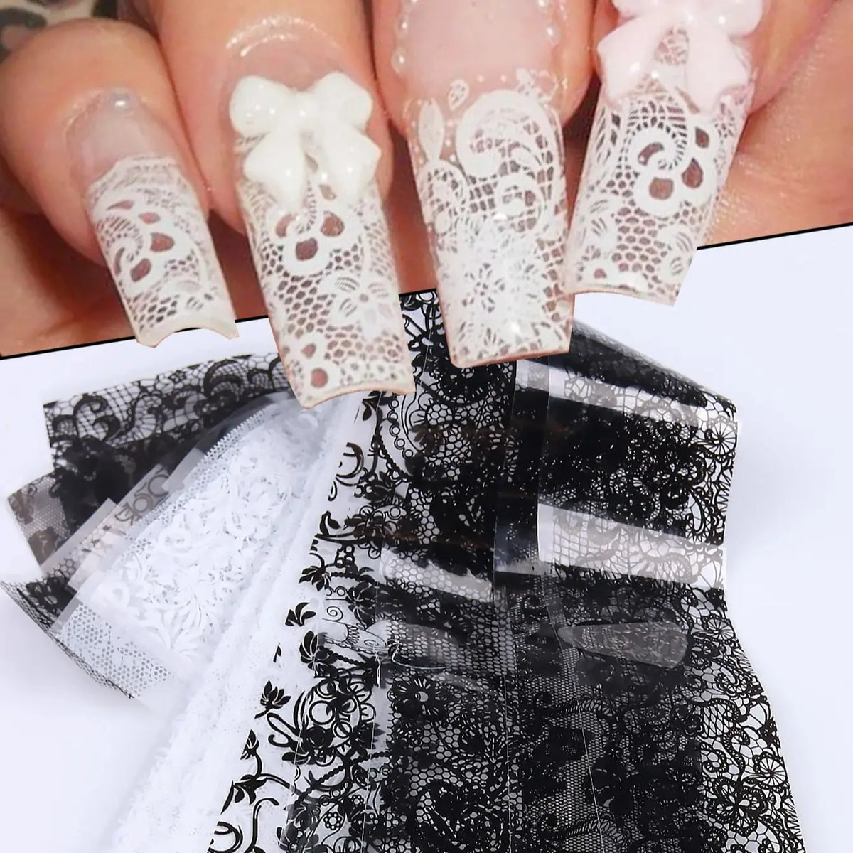 Une main montre des autocollants de faux ongles en dentelle blanche et noire sur les ongles, avec un tissu en dentelle noire 