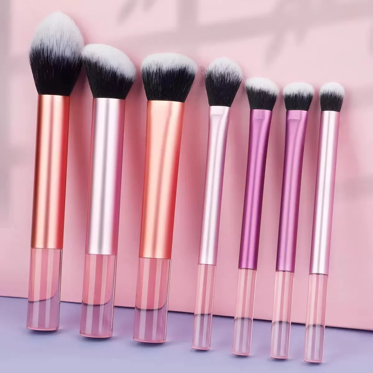Un juego de doce brochas de maquillaje profesionales en varios tonos de rosa y oro rosado.