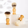 Un juego de brochas de afeitar y facial de madera con cerdas rubias claras, mostradas sobre una superficie blanca.