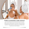 A woman is using a white pore cleansing device on her face in a bathroom setting.