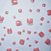 A collection of pink and nude press-on acrylic false toenails scattered across a white background.