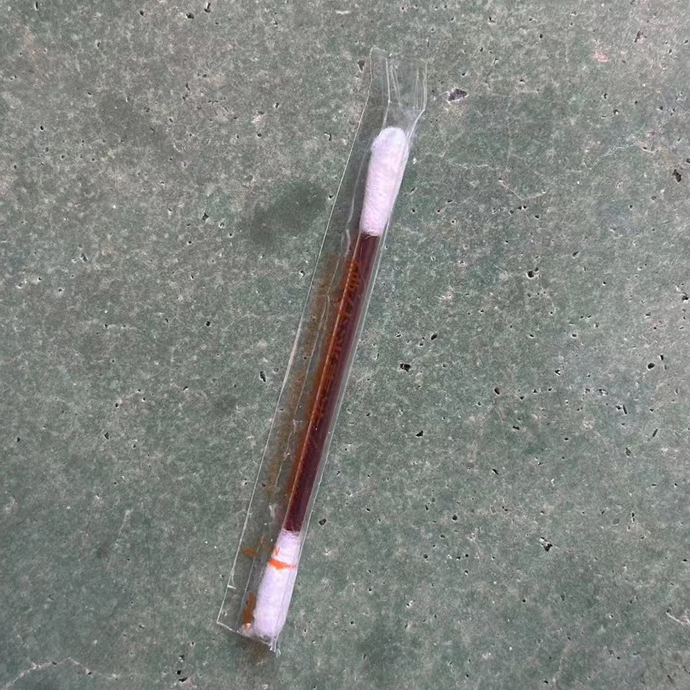 A clear plastic tube containing a white instant iodine swab for wound care.