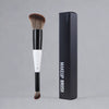 A black makeup brush with a white ferrule and bristles is shown next to its packaging box.