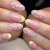 Close-up of a hand displaying press-on acrylic flower nails with pink and white floral designs.