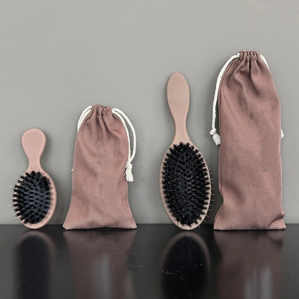 A set of matte pink boar bristle hair extension brushes in a fabric pouch.