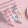 Un paquete de cuatro cepillos de dientes de ositos de peluche infantiles en varios colores pastel sobre un fondo rosa.