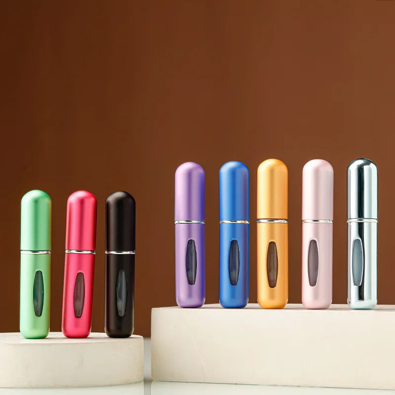 A row of twelve portable refillable perfume bottles in various colors standing on a white surface against a brown background.