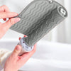 A hand holds a gray silicone heat resistant mat for hair styling tools, showing its textured surface.