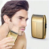 A man is holding a gold-colored electric foil shaver, demonstrating the product.