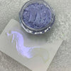 A jar of purple glitter nail art powder is shown next to a white swatch on a silver surface.