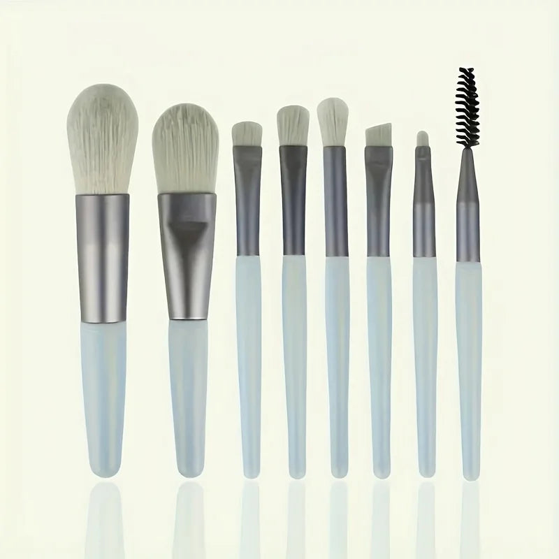 A set of various makeup brushes with soft synthetic bristles and light blue handles displayed vertically.