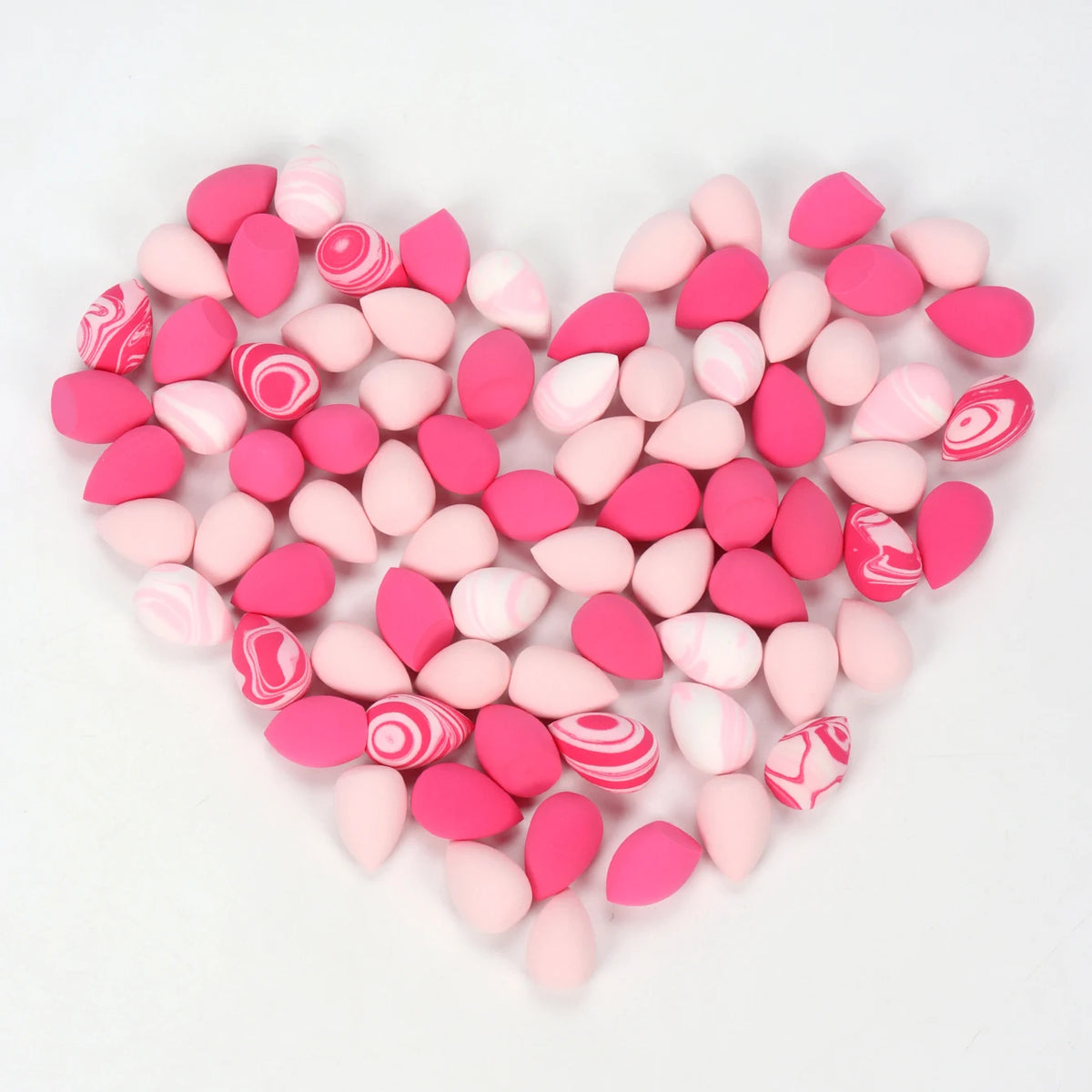 A heart shape composed of pink and red reusable expandable makeup sponges.