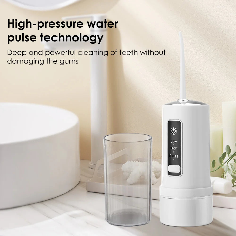 A white portable high-pressure oral irrigator device next to a glass of water and a toilet bowl.