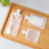 A set of three clear refillable squeeze bottles for toiletries placed on a wooden tray.