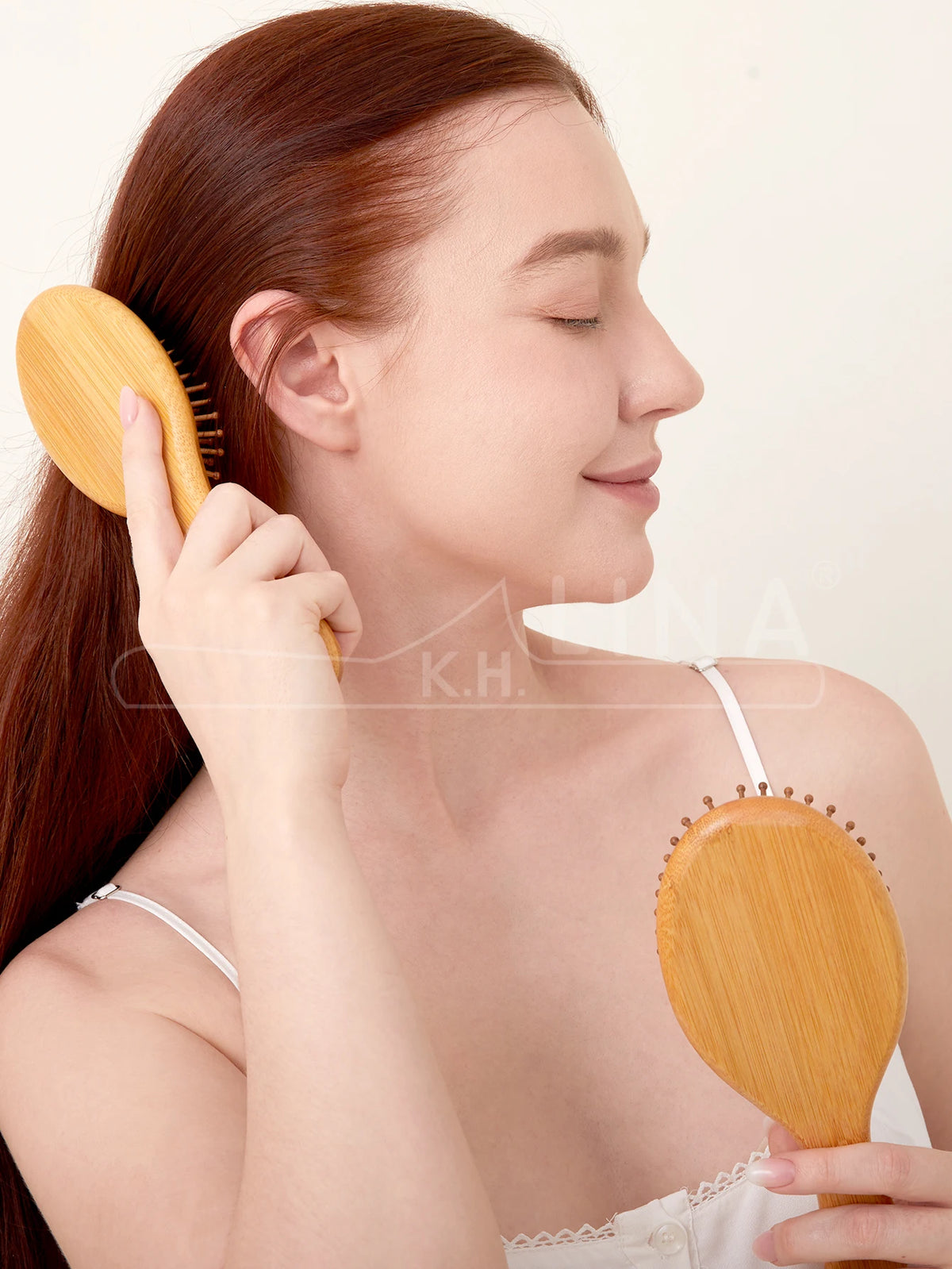 A woman is using a wooden hair brush on her hair, demonstrating its use for detangling or scalp massage.