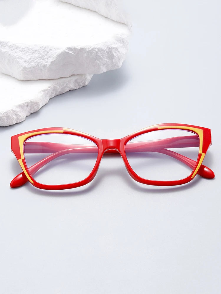 A pair of red cat eye reading glasses resting on a white surface.