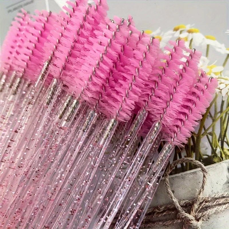 A bundle of pink and black disposable eyelash and eyebrow makeup brushes with sparkly pink bristles.