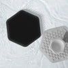 A black silicone facial cleaning and massage brush resting on a white, wet surface.