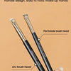 A pair of black precision makeup brushes, including a flat blade and an arc brush head, are shown being held by a hand.