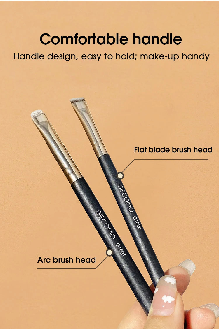 A pair of black precision makeup brushes, including a flat blade and an arc brush head, are shown being held by a hand.