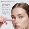 A woman is using a pink eye massage instrument on her face to rejuvenate the skin.