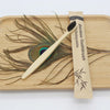 A bamboo toothbrush is shown resting on a wooden cutting board with a design of flowing hair.
