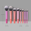Eight makeup brushes in various sizes and shades of pink and coral displayed vertically.