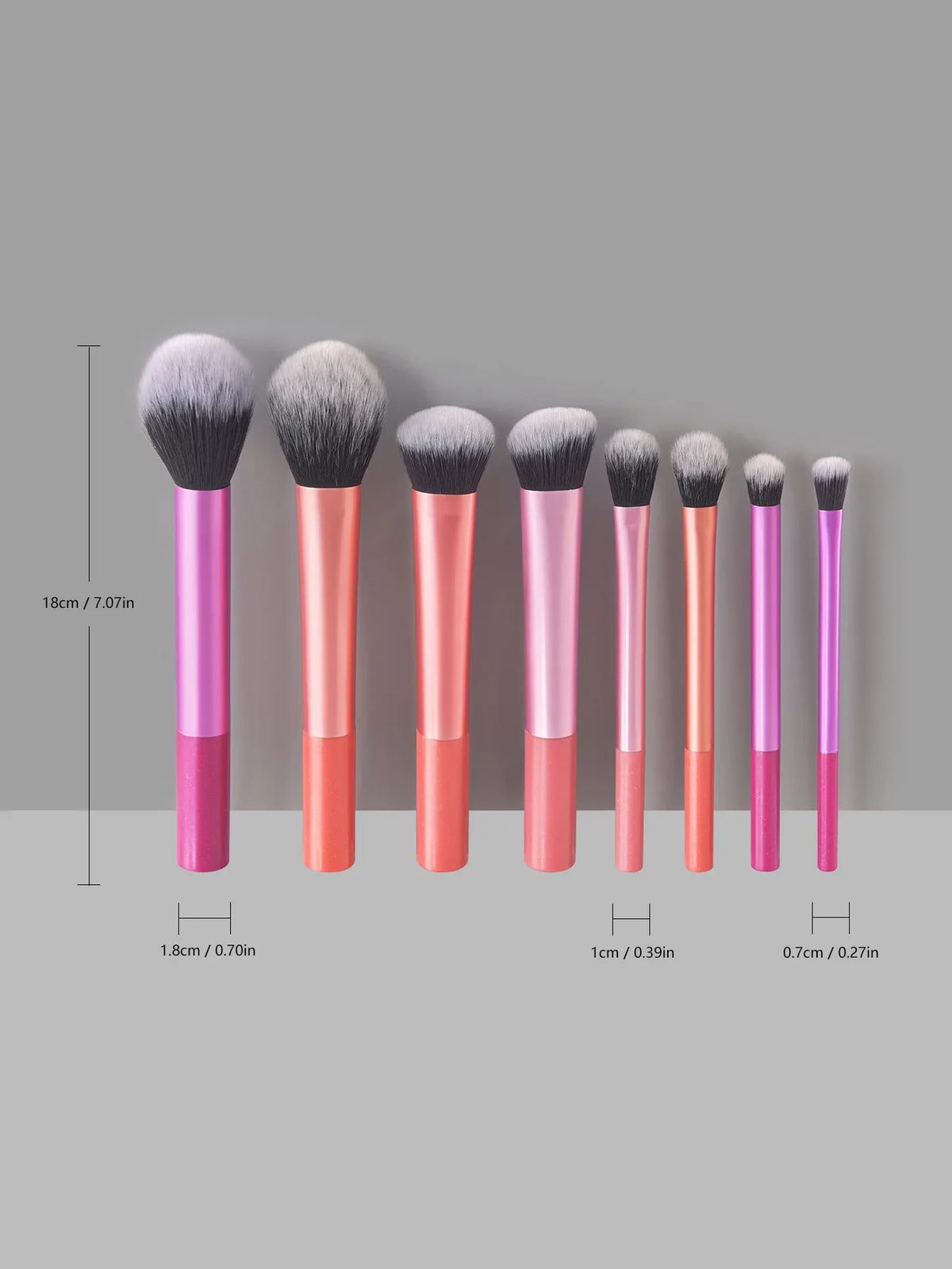 Eight makeup brushes in various sizes and shades of pink and coral displayed vertically.