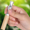 A hand holds a natural wooden stop smoking stick diffuser with a silver cap against a blurred green background.