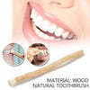 A close-up of a person's mouth showing teeth and a wooden miswak toothbrush.